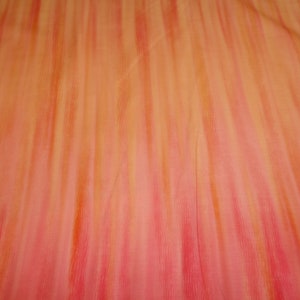 May include: A close-up of a fabric with a gradient of orange and pink stripes. The fabric has a soft, flowing texture.