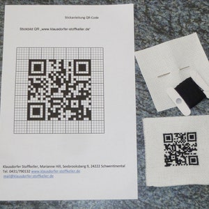 Op de afbeelding: Een zwart-wit QR-code kruissteekpatroon met instructies en een klein stukje zwarte borduurgaren.