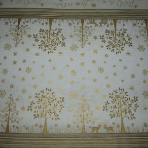 Könnte beinhalten: Weißer Stoff mit einem goldenen Metallic-Druck von stilisierten Bäumen und Schneeflocken. Der Stoff hat einen dezenten Schimmer.