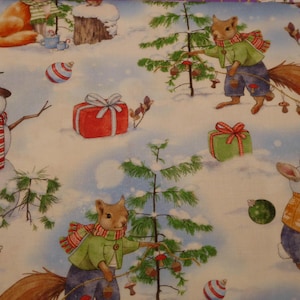 Op de afbeelding: Een grillig winterlandschapstof met cartoon dieren die kerstbomen versieren. Sneeuwmannen, eekhoorns en konijnen worden getoond in een besneeuwd landschap met cadeaus en ornamenten. De achtergrond is lichtblauw.