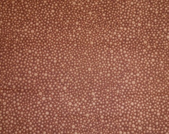 May include: A brown fabric with a white polka dot pattern. The dots are of varying sizes and are randomly distributed across the fabric.