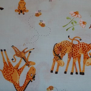 Könnte beinhalten: Ein hellblauer Stoff mit einem Muster aus orangefarbenen Giraffen und Bienen. Die Giraffen sind in verschiedenen Posen dargestellt, darunter stehend, liegend und spielend. Die Bienen fliegen um die Giraffen herum.