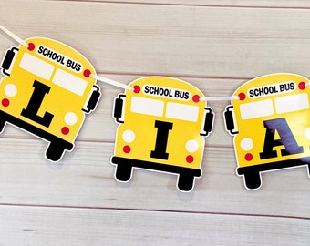 Peut inclure: Une bannière sur le thème du bus scolaire jaune avec le nom "LIAM" écrit sur chaque bus. Chaque bus a les mots "SCHOOL BUS" imprimés en haut.