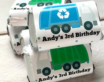 May include: A stack of small wrapped chocolate bars with a blue and green garbage truck design. The wrappers have white backgrounds with black text that reads "Andy's 3rd Birthday".