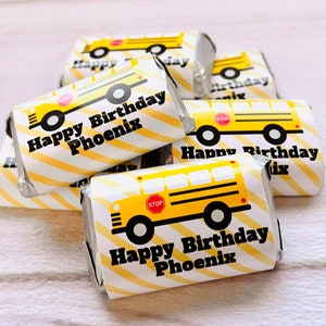 May include: Yellow and black school bus themed chocolate bar wrappers with the text "Happy Birthday Phoenix" printed on them.