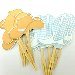 May include: A set of 10 cowboy themed cupcake toppers. The toppers feature a brown cowboy hat and a blue and white gingham cowboy boot. The toppers are attached to wooden skewers.