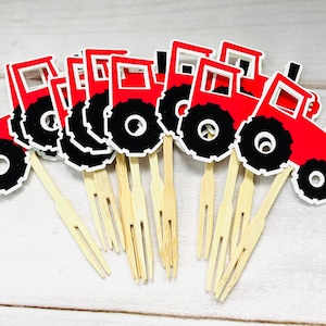 May include: A set of 10 red and black tractor cupcake toppers with bamboo picks. The tractors have black wheels and a white outline.