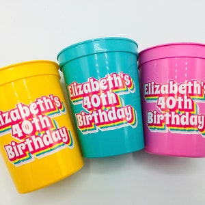 Puede incluir: Tres vasos de pl&aacute;stico de colores: amarillo, turquesa y rosa. Cada vaso tiene el texto "Elizabeth's 40th Birthday" en una fuente retro. Ideales para una fiesta.