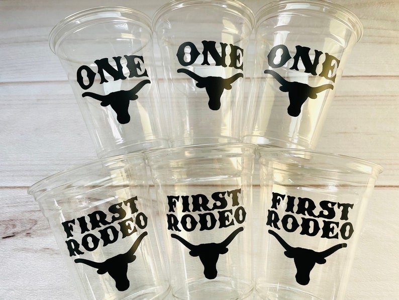 K&ouml;nnte beinhalten: Sechs durchsichtige Plastikbecher mit schwarzen Vinyl-Aufklebern. Drei Becher sagen "ONE" mit einer schwarzen Silhouette eines Longhorn-Rinds. Drei Becher sagen "FIRST RODEO" mit einer schwarzen Silhouette eines Longhorn-Rinds.