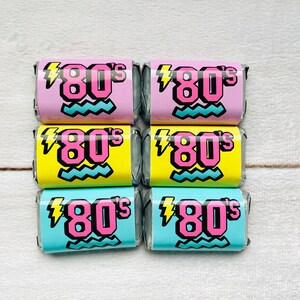 Pu&ograve; includere: Sei piccoli caramelle avvolti con un tema anni '80. Le caramelle sono avvolte in rosa, giallo e blu con un fulmine e linee ondulate. Il testo sulle caramelle dice "80's".