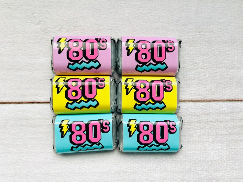 Pu&ograve; includere: Sei piccoli caramelle avvolti con un tema anni '80. Le caramelle sono avvolte in rosa, giallo e blu con un fulmine e linee ondulate. Il testo sulle caramelle dice "80's".