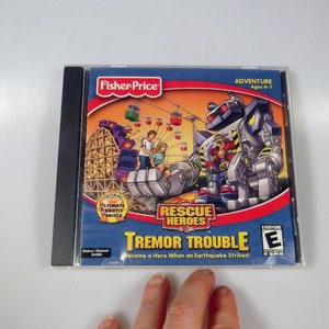 May include: A computer game CD case featuring a cartoon robot and the text "Rescue Heroes: Tremor Trouble". The game is rated E for Everyone by the ESRB.