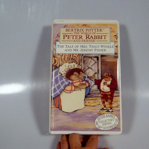 May include: A VHS tape featuring Beatrix Potter's The World of Peter Rabbit and Friends. The cover shows Mrs. Tiggy-Winkle and Mr. Jeremy Fisher. The title of the episode is "The Tale of Mrs. Tiggy-Winkle and Mr. Jeremy Fisher". The tape is a collector's edition celebrating the 100th anniversary of Peter Rabbit.