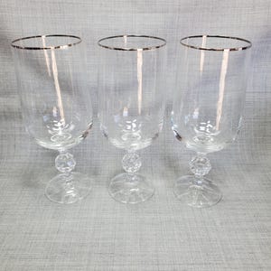 May include: Three clear glass goblets with a silver rim and a faceted ball stem.