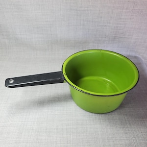 May include: A green enamel saucepan with a black handle. The saucepan is empty and has a black rim around the top.