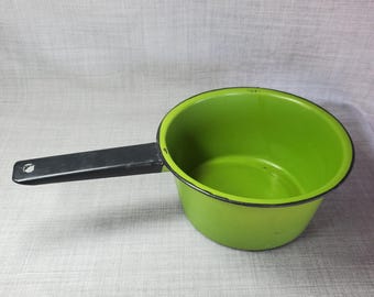 Puede incluir: Una cacerola de esmalte verde con un mango negro. La cacerola está vacía y tiene un borde negro alrededor de la parte superior.