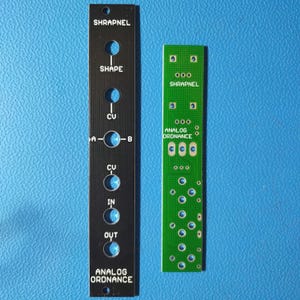 May include: Black and green circuit boards with the text "SHRAPNEL", "SHAPE", "CU", "A", "B", "IN", "OUT", "ANALOG ORDNANCE" on the black board and "SHRAPNEL", "ANALOG ORDNANCE" on the green board.