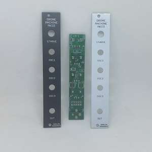 Puede incluir: Tres placas de circuito electrónico. Dos son rectangulares con texto: "DRONE MACHINE MKIII", "STARVE", "OSC1", "OSC2", "OSC3", "OUT" y "ANALOG ORDNANCE". Una es negra, la otra plateada. La tercera es verde con componentes electrónicos.