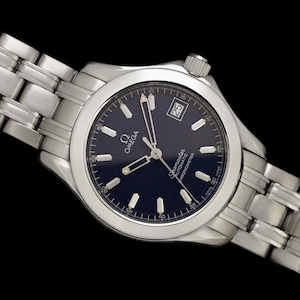 May include: A stainless steel Omega Seamaster watch with a dark blue dial. The watch features a date display at the 3 o'clock position and a silver-toned bracelet. The watch is set against a black background.
