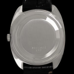 May include: A silver-toned wristwatch with a black leather band. The watch case back features a circular design with engraved numbers. The watch is set against a black background.