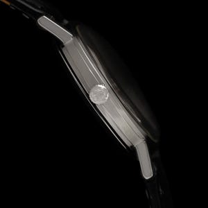 May include: Side view of a silver wristwatch with a black watch face and a black leather band. The watch has a round face and a small crown. The watch is set against a black background.