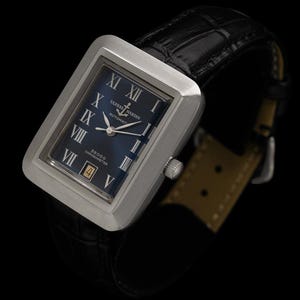 May include: A rectangular stainless steel wristwatch with a dark blue face and black leather band. The watch face features Roman numerals and the brand name "Ulysse Nardin". The watch has a date display and a silver crown.