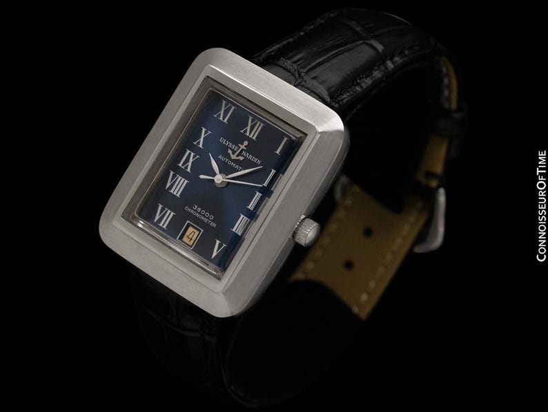 May include: A rectangular stainless steel wristwatch with a dark blue face and black leather band. The watch face features Roman numerals and the brand name "Ulysse Nardin". The watch has a date display and a silver crown.