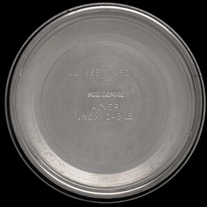 May include: A close-up of the back of a silver-colored watch. The watch back has the words "ULYSSE NARDIN" and other text in a circular pattern. The watch back is made of stainless steel.