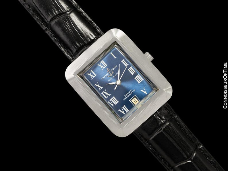 May include: A rectangular stainless steel watch with a blue face and Roman numeral hour markers. The watch features a date window at the 4 o'clock position and is set on a black leather band. The watch face has the text "Ulysse Nardin" and "Automatic".