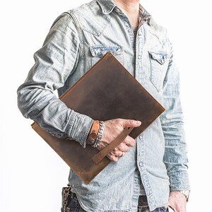 May include: A brown leather portfolio with a handle. The portfolio is distressed and has a vintage look.