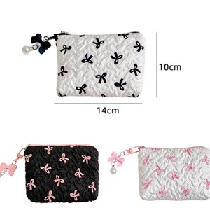 Op de afbeelding: Een witte, zwarte en roze pouch met strikpatroon en ritssluiting. De pouch is 14 cm lang en 10 cm hoog. De pouch heeft een strik- en parelbedel aan de rits. Extra pouches in zwart en wit worden ook getoond.
