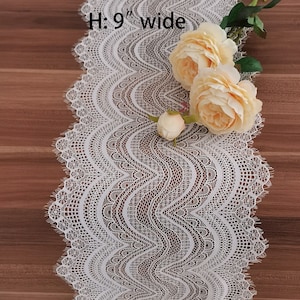 Peut inclure: Un chemin de table en dentelle blanche avec un bord festonné et un motif ondulé. Le chemin de table mesure 9 pouces de large et est décoré de fleurs artificielles.