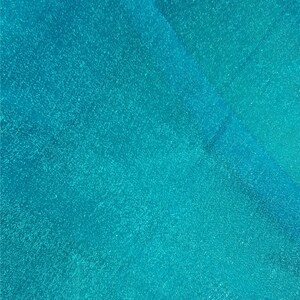 May include: A close-up of a turquoise blue surface with a subtle sparkle. The surface has a smooth, even texture.