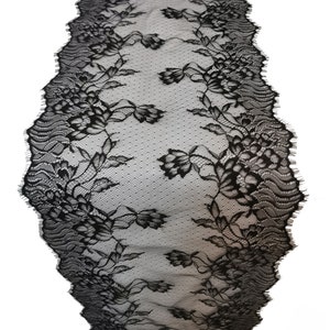 Könnte beinhalten: Schwarzer Tischläufer aus Spitze mit floralem Design. Der Läufer hat einen gewellten Rand und besteht aus einem zarten, transparenten Stoff. Das florale Muster umfasst detaillierte Blumen und Blätter.