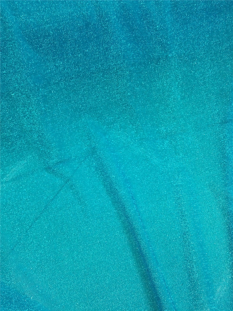 May include: A close-up of a turquoise blue fabric with a sparkly, textured surface.