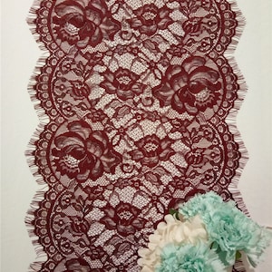 Peut inclure: Bordure en dentelle de couleur bordeaux avec un bord festonné et un motif floral. La dentelle est délicate et complexe, avec une texture douce et fluide.