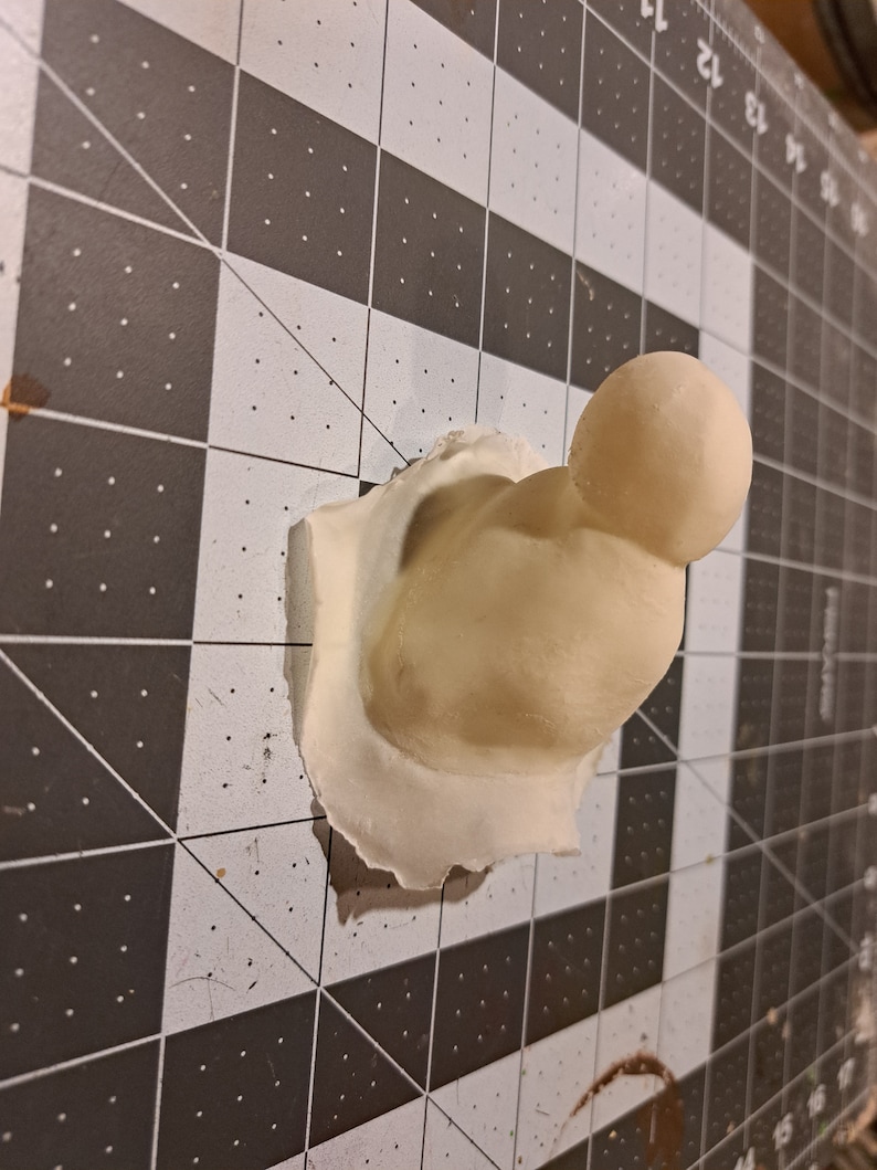 May include: A white, 3D printed, abstract sculpture with a rounded top and a textured surface.