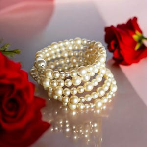 May include: A multi-strand pearl bracelet with a silver clasp. The bracelet is made of white pearls and is wrapped around itself several times.