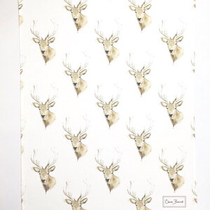 May include: White tea towel with a repeating pattern of watercolour deer heads. The deer have brown antlers and brown faces. The text "Clara Baird" is in the bottom right corner.