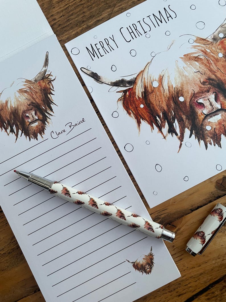 Pu&ograve; includere: Un blocco note bianco con carta rigata e un'illustrazione di una mucca delle Highlands marrone e bianca. Il blocco note ha una firma a mano che dice "Clare Baird". Una penna con un motivo di mucca delle Highlands marrone e bianca &egrave; appoggiata sul blocco note. Un biglietto bianco con un'illustrazione di una mucca delle Highlands marrone e bianca e il testo "Merry Christmas" &egrave; sullo sfondo.