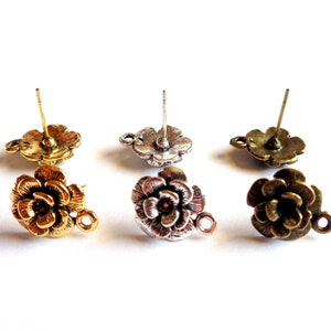 Peut inclure: Trois paires de supports de boucles d'oreilles en forme de fleur avec une tige et une boucle. Les supports sont en or, argent et bronze.