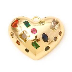 Peut inclure: Un pendentif doré en forme de cœur orné de diverses pierres précieuses colorées. Le pendentif comporte une boucle en haut pour l'accrocher et est orné de pierres rouges, vertes, roses et transparentes.