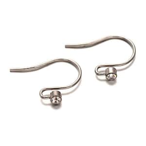 Peut inclure: Une paire de crochets d'oreille argentés avec un petit cristal transparent à l'extrémité de chaque crochet.