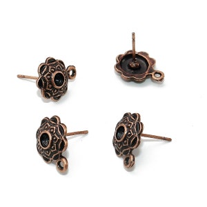 Può includere: Quattro ritrovamenti di orecchini in rame antico con un design floreale decorativo e un anello per attaccare un ciondolo o una perla. I ritrovamenti hanno un perno per la perforazione e un piccolo anello sul lato.
