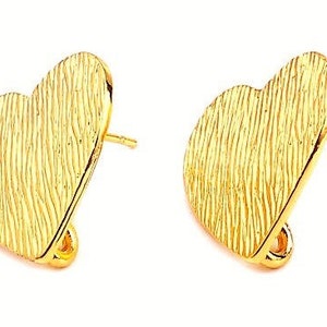 Peut inclure: Une paire de boucles d'oreilles à clous dorées en forme de cœur. Les boucles d'oreilles ont une surface texturée avec des lignes verticales. Les tiges et les fermoirs sont également dorés. Les boucles d'oreilles sont sur fond blanc.