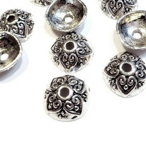 Peut inclure: Des capuchons de perles en métal argenté avec un motif tourbillonnant orné. Les capuchons de perles ont une forme carrée arrondie avec un trou central. Ces composants décoratifs sont parfaits pour la fabrication de bijoux et les projets d'artisanat.