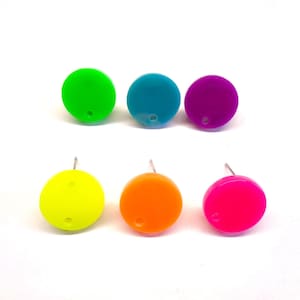 Pode incluir: Seis brincos de tachas coloridos em verde néon, azul-petróleo, roxo, amarelo, laranja e rosa. Cada brinco é um pequeno disco redondo com um pino para perfurar. Os brincos estão dispostos em duas filas de três sobre um fundo branco.