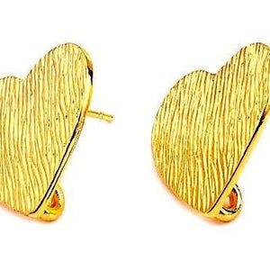Peut inclure: Une paire de composants de boucles d'oreilles en forme de cœur doré avec une surface texturée et ondulée. Chaque pièce comprend une tige à l'arrière pour la fixation et une petite boucle en bas pour suspendre des éléments ou des breloques.