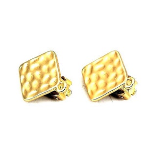 Peut inclure: Une paire de boucles d'oreilles clip dorées de forme carrée. Chaque boucle d'oreille présente une surface texturée martelée et un mécanisme de clip décoratif. Les boucles d'oreilles sont sur fond blanc.