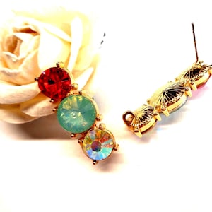 Peut inclure: Une paire de boucles d'oreilles dorées composées de trois cristaux circulaires à facettes de couleur rouge, vert clair et blanc irisé. Les boucles d'oreilles présentent une disposition linéaire verticale avec une tige de fermeture.